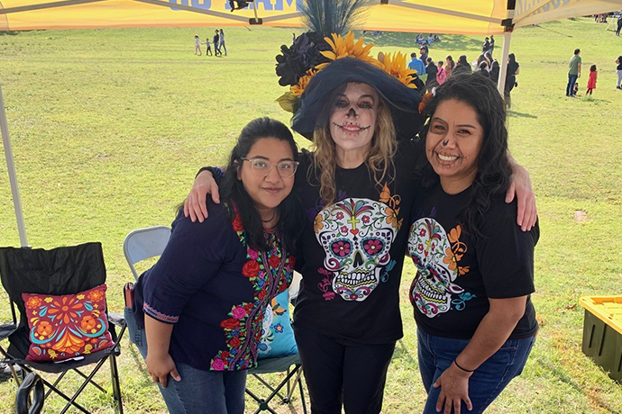 Dr. Amy Bell and two students pose at the 2023 Dia de los Muertos parade